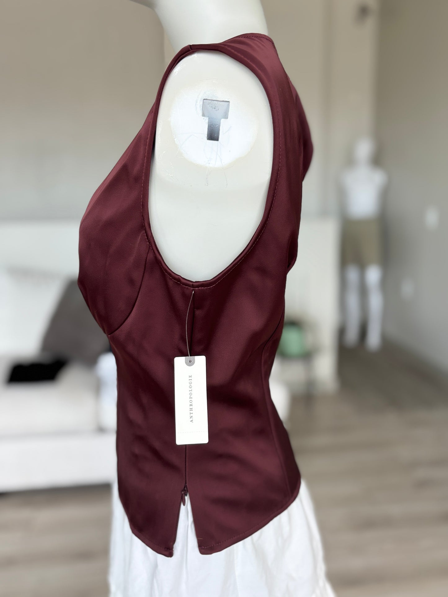 Anthropologie oxblood corset-inspired top with sculpted bust shaping, substantial satin-look fabric, and a fitted silhouette.