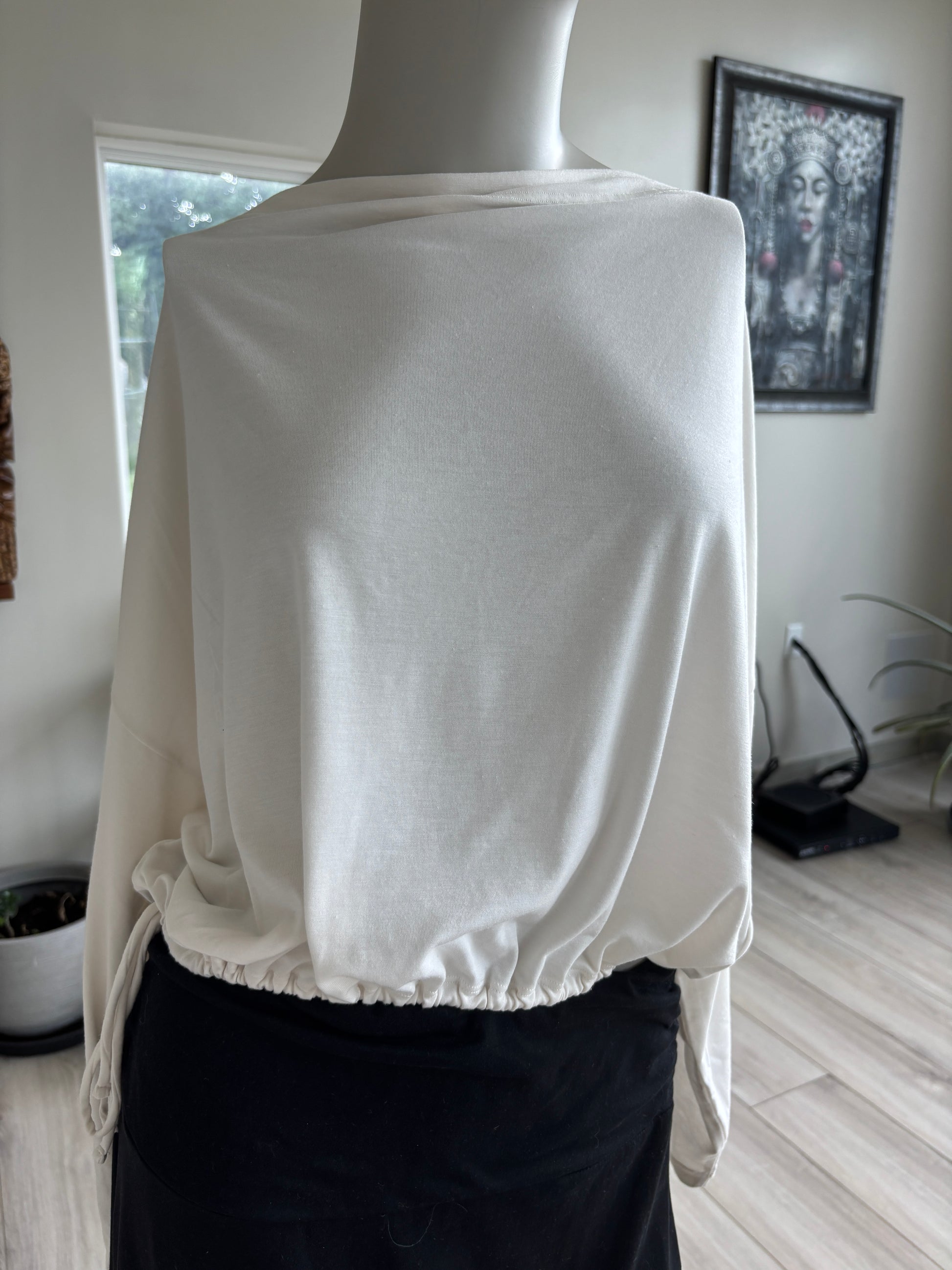 Athleta warm ivory yoga top with a draped boat neckline, long tapered sleeves, and adjustable cinch hem.