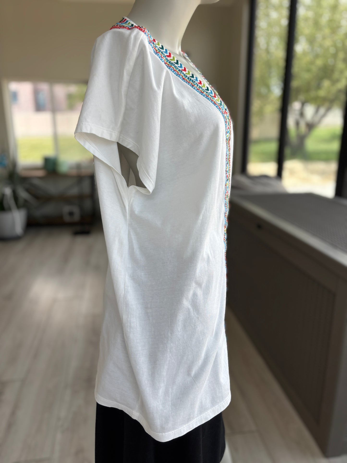 Colorful embroidered white cotton blouse styled with a relaxed silhouette, soft texture, and effortless summer-ready charm.