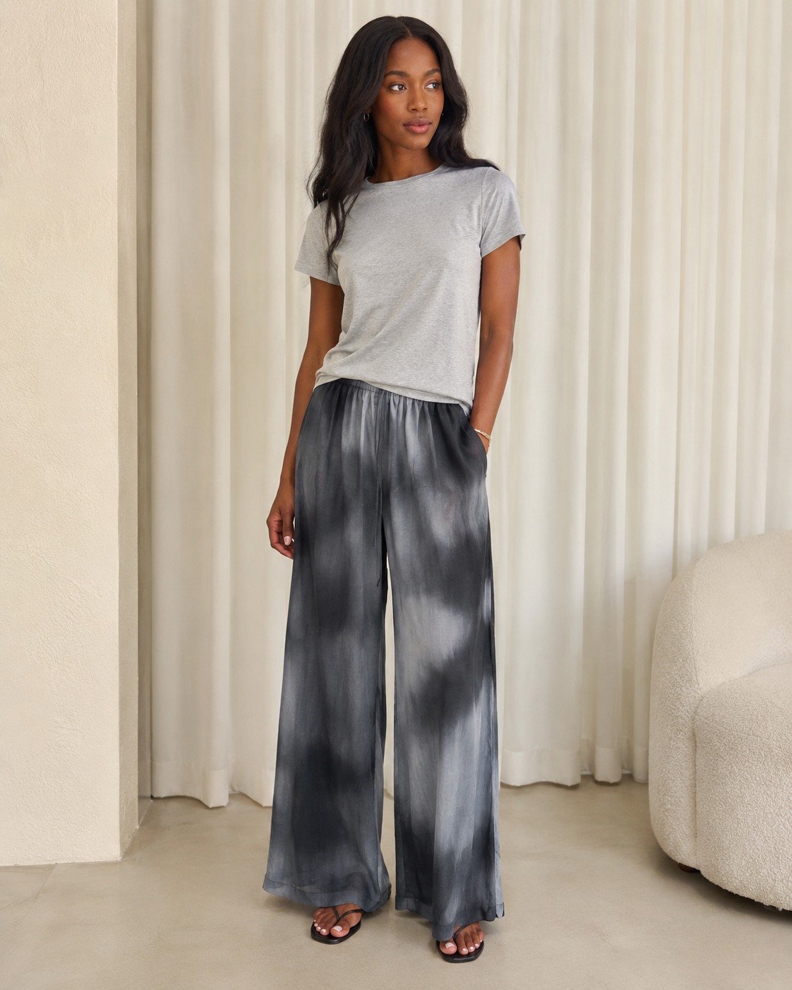 DISSH black and gray tie-dye wide-leg pants with a light gray T-shirt and sandals.