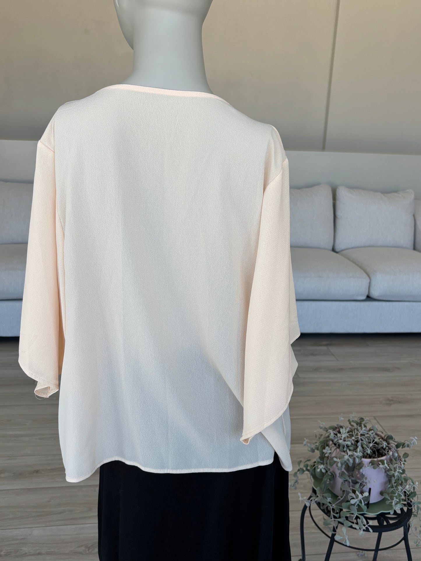 Elegant peach blouse with flowing sleeves and rounded hem for dressy casual wear
