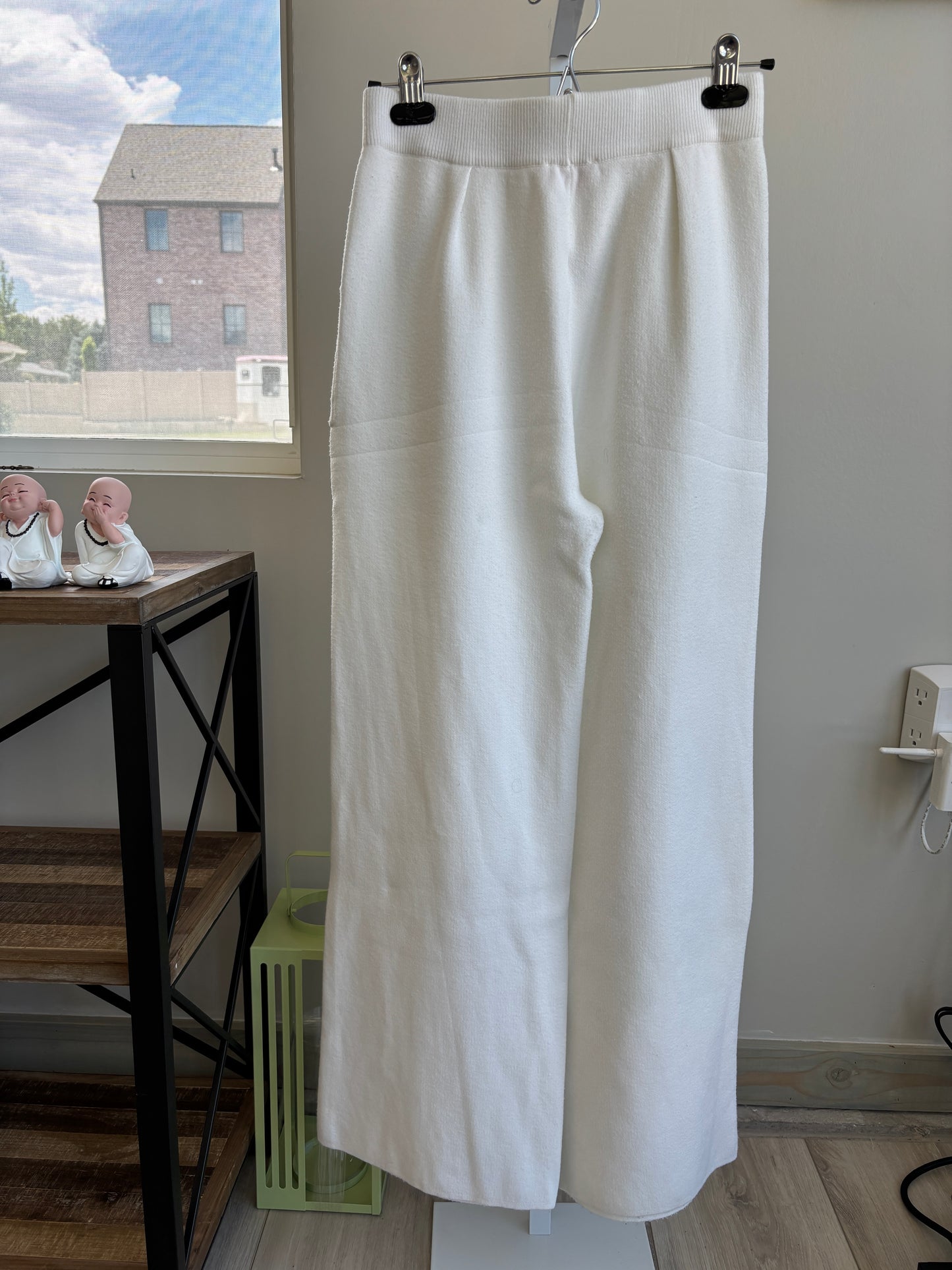 Flat lay of Pink Lily cream wide leg knit lounge pants on a pink background with cozy accessories.