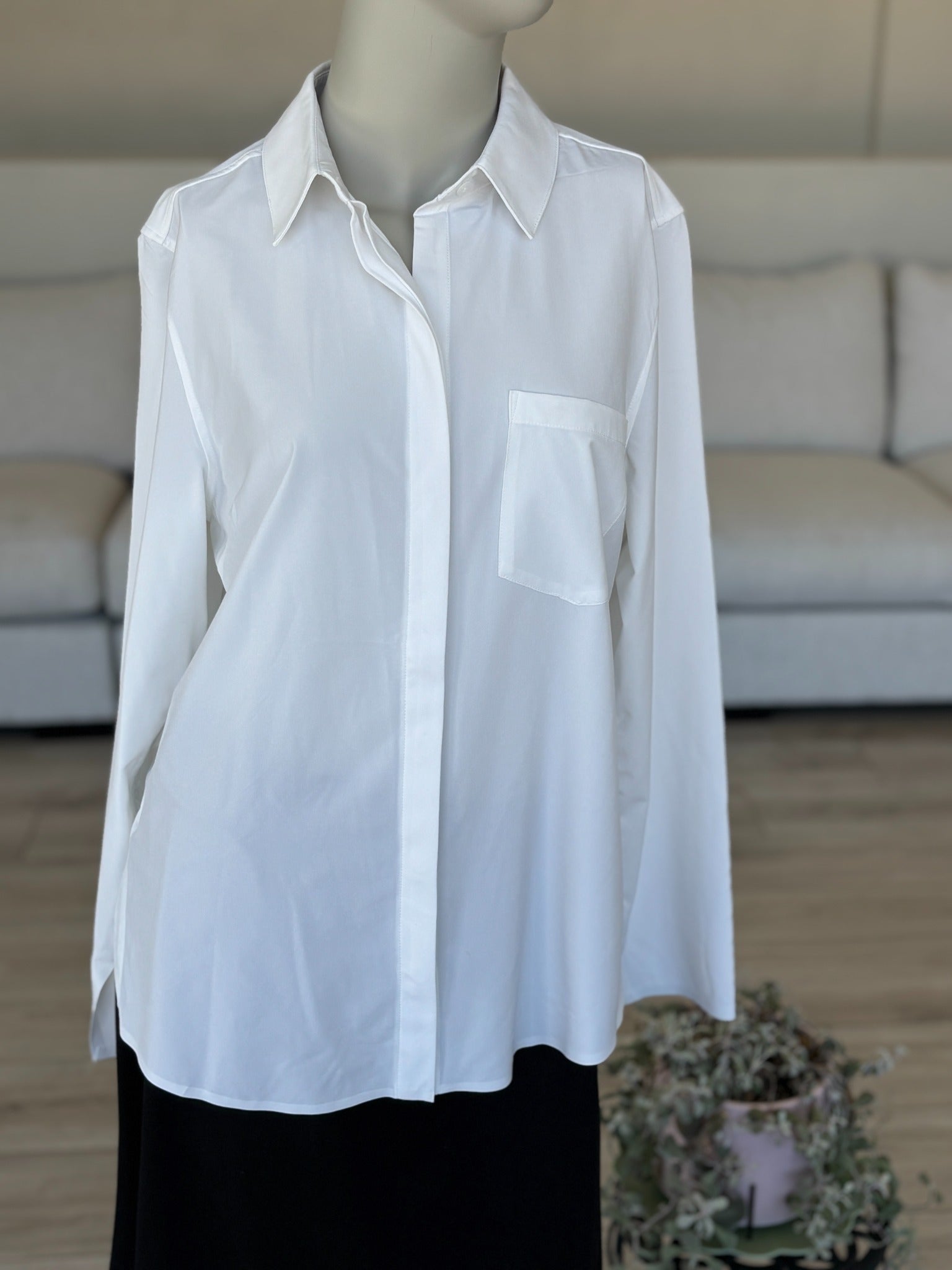Women’s oversized white blouse with longer back hem styled with black ankle boots