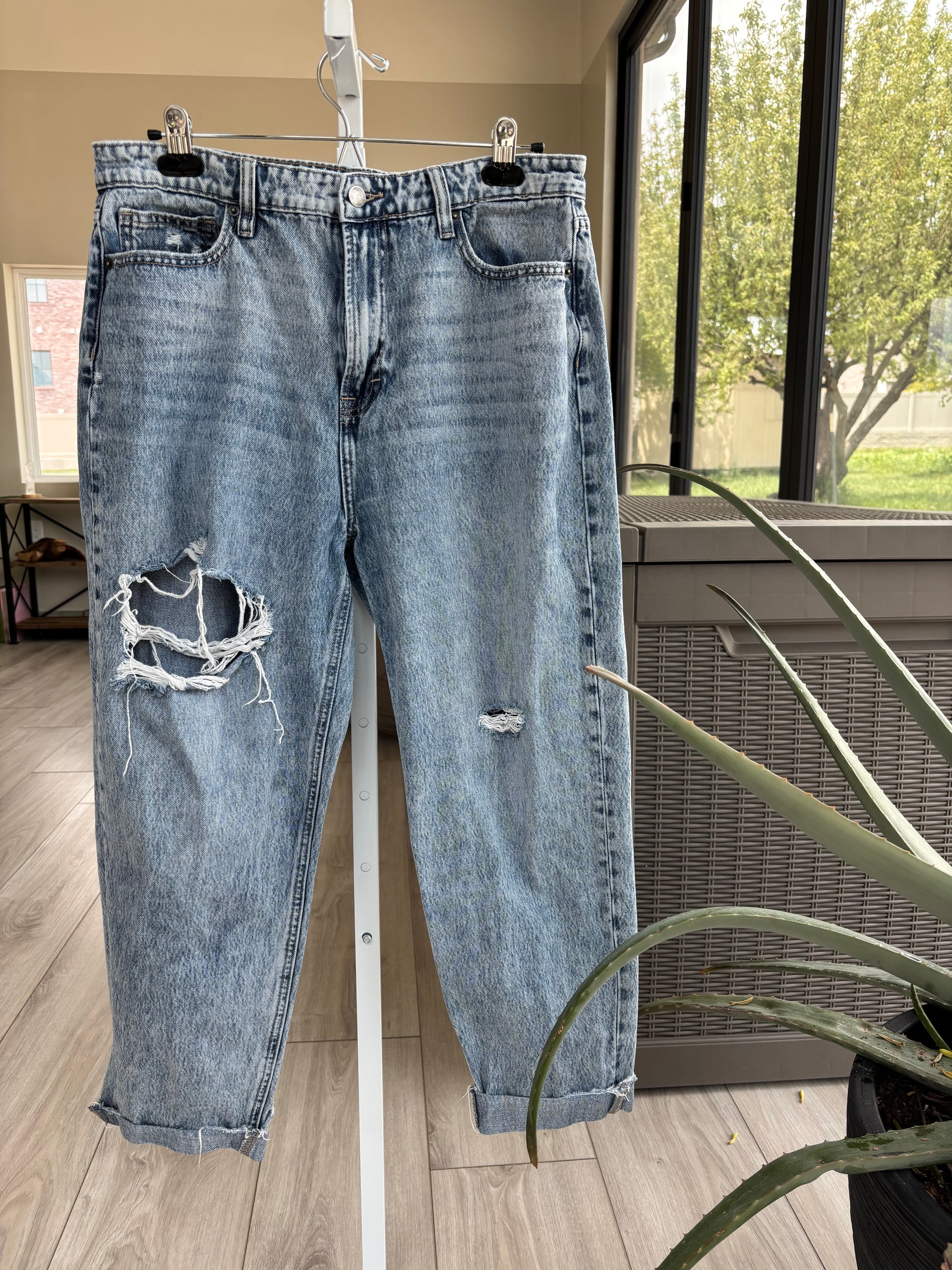 Pre-loved light wash jeans with baggy tapered silhouette and distressed knee holes
