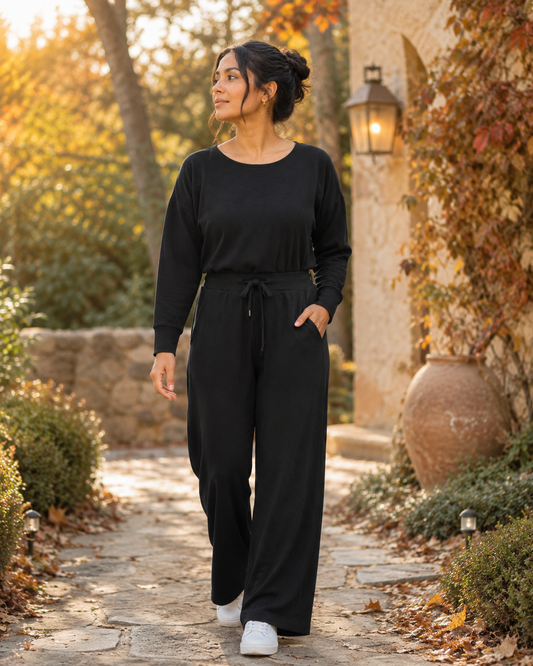 SPANX AirEssentials women’s black long-sleeve wide-leg jumpsuit with boat neckline, defined waist, and pockets in size M.