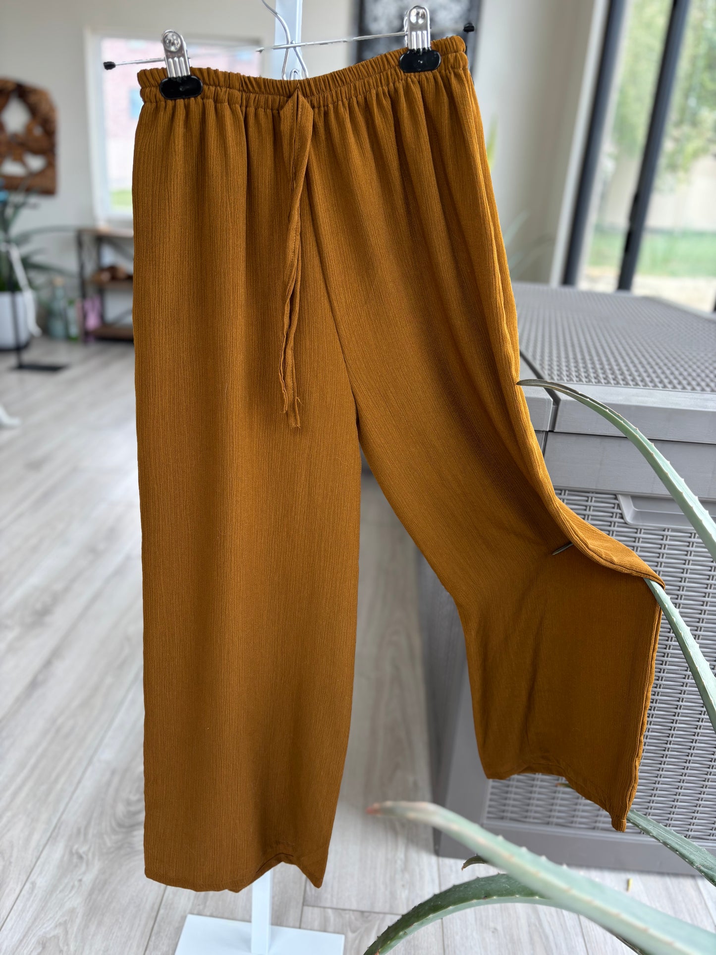 wide leg rust colored flowy pants with elastic waist and decorative tassel. Gauze fabric detail.