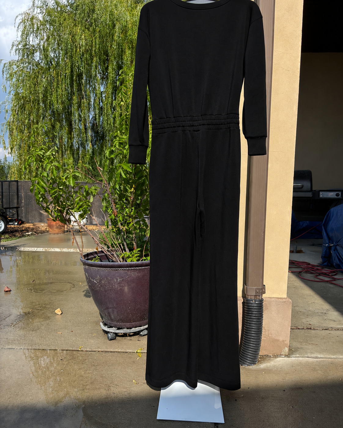 Women’s SPANX black travel jumpsuit in cloud-soft AirEssentials fabric with long sleeves, a defined waist, and wide legs.