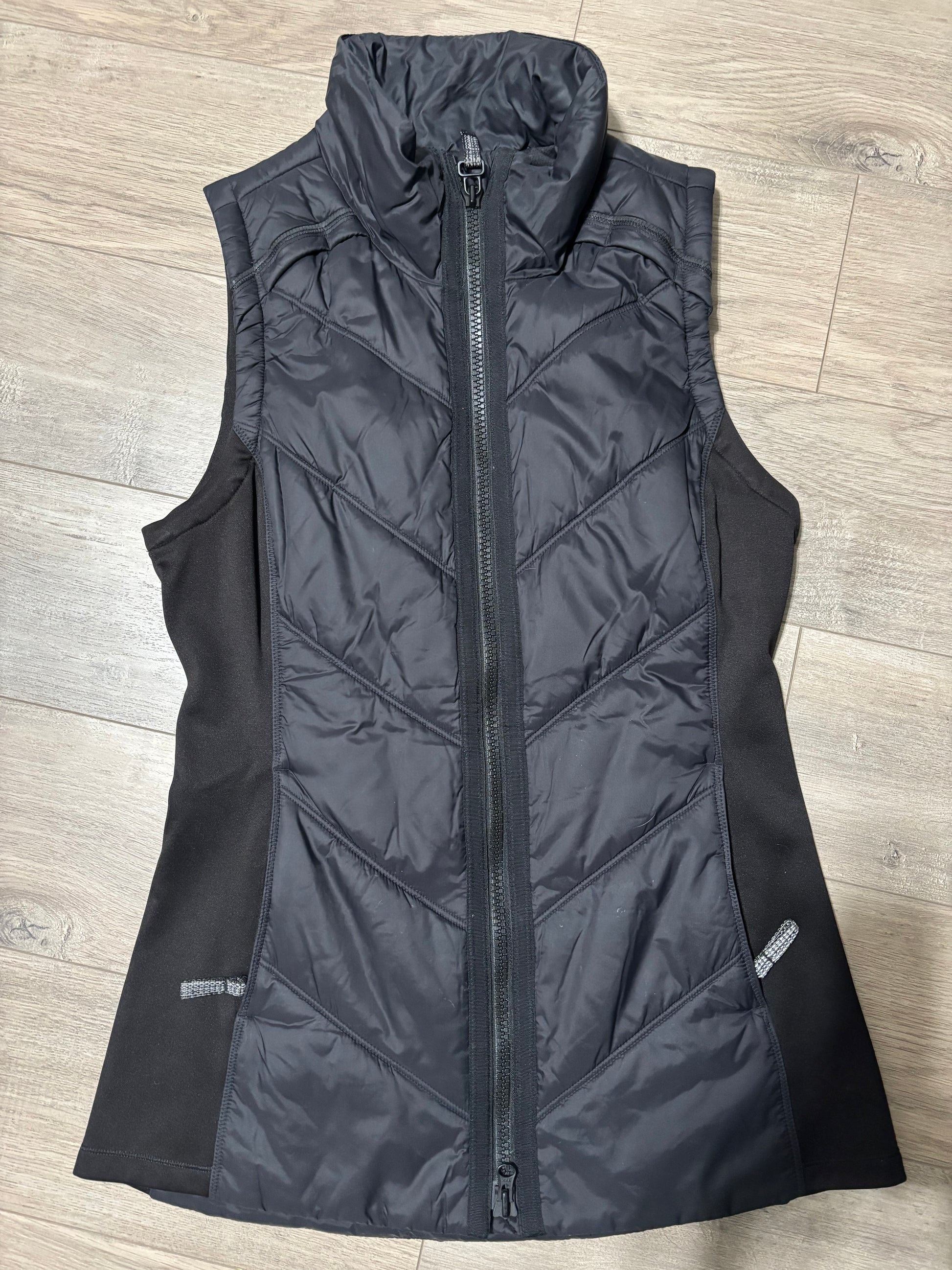 Flat lay Athleta Vest zipper and pocket tassels flattering chevron stitiching.  for warmth and beauty.